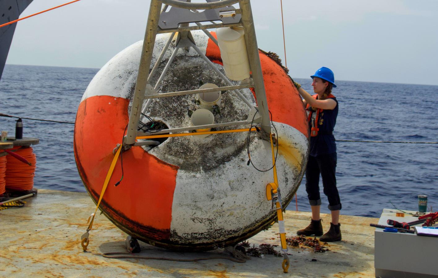 A crew member works on a bouy on the deck of a ship