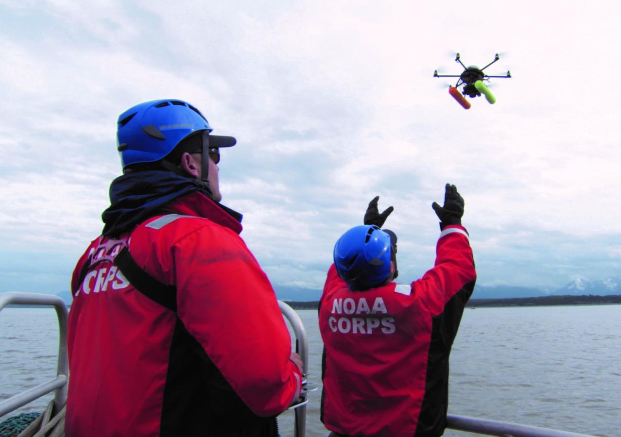 Two NOAA Corps officers launch a hexacopter drone into the air