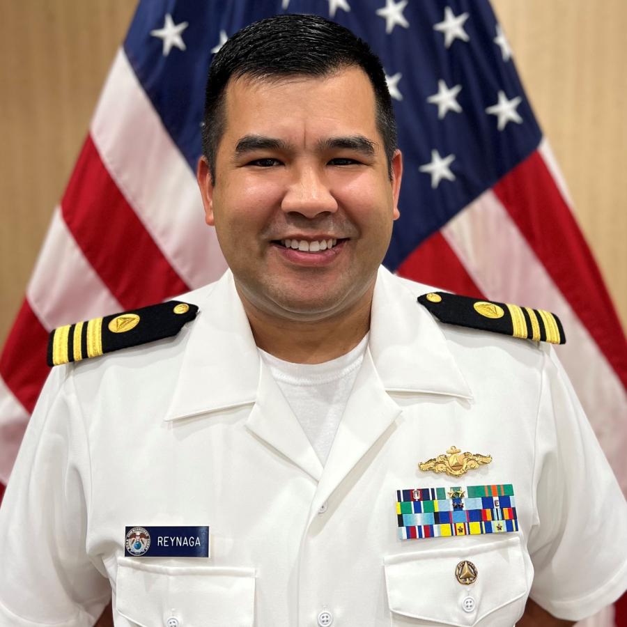 Lieutenant Commander Andrew Reynaga posed in front of the American flag.