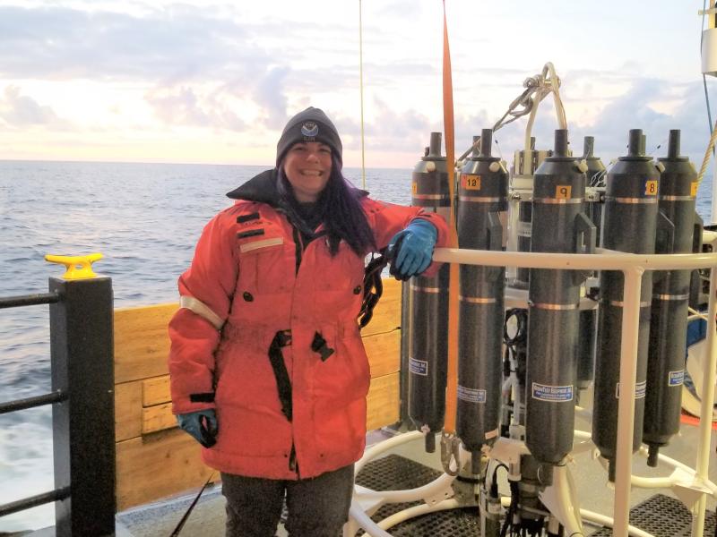 A female senior survey technician on aboard a ship with a water sampling instrument