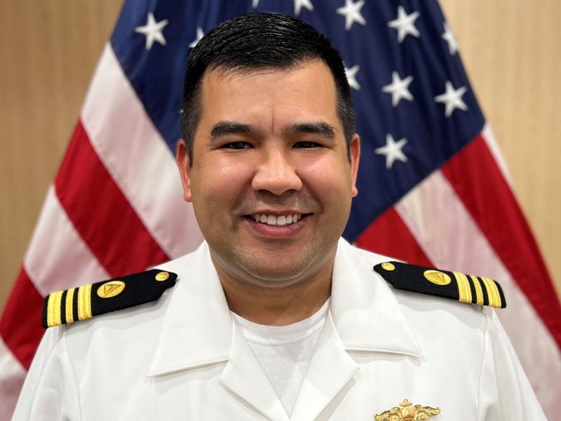 Lieutenant Commander Andrew Reynaga posed in front of the American flag.