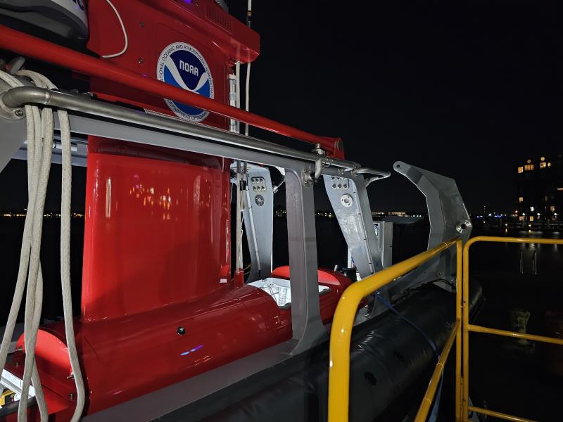 The red DriX uncrewed marine system sits in its gray gondola at night