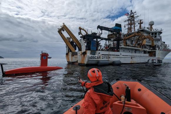 An uncrewed surface vehicle behind NOAA Ship Oscar Dyson