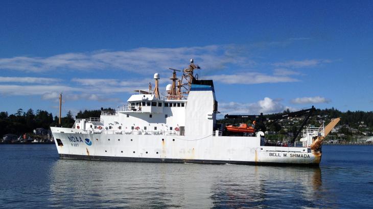 A white ship with Newport Oregon in the background on a clear day