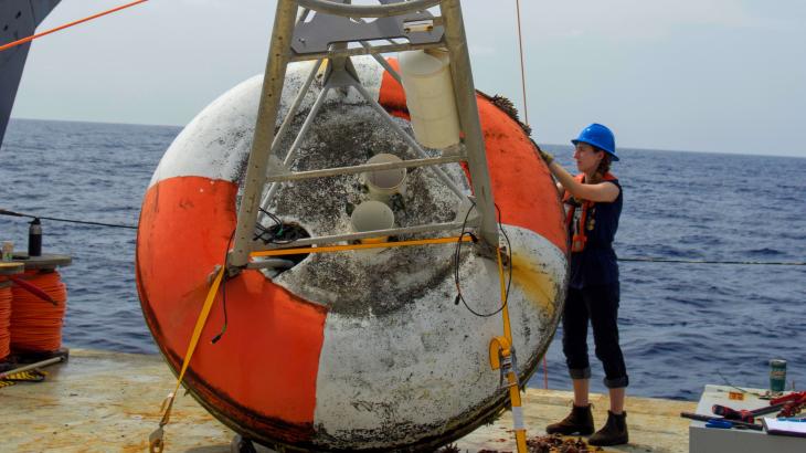 A crew member works on a bouy on the deck of a ship