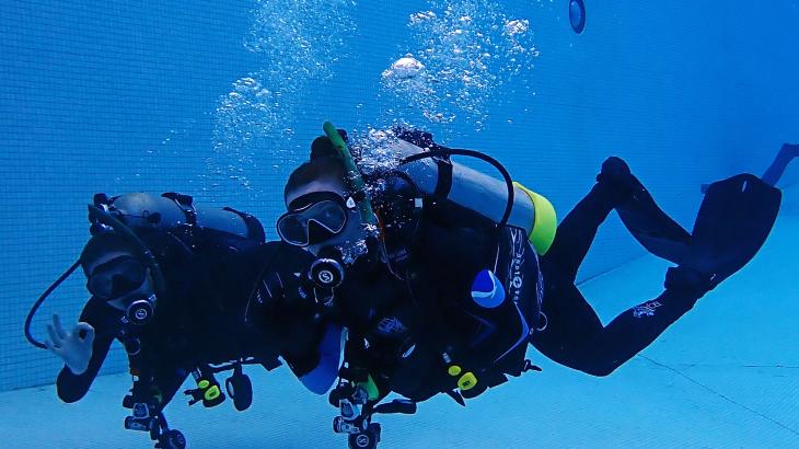 A pair of NOAA scuba dives under water in a swimming pool