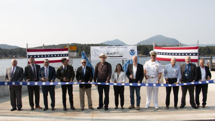 A long line of special guests, including NOAA Administrator Dr. Rick Spinrad (5th from the left), participate in a ribbon-cutting ceremony for the NOAA-renovated port facility in Ketchikan, Alaska, on August 21, 2023.