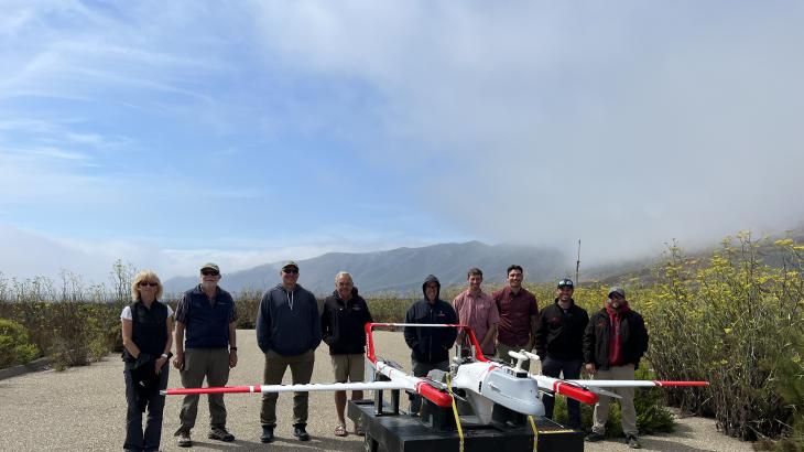 A group of people standing behind an uncrewed aircraft