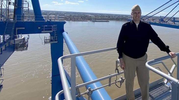 RDML Ben Evans stands atop a structure over the water.