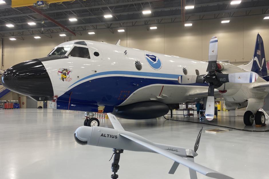 NOAA WP-3D Orion aircraft with model of a small gray uncrewed aircraft