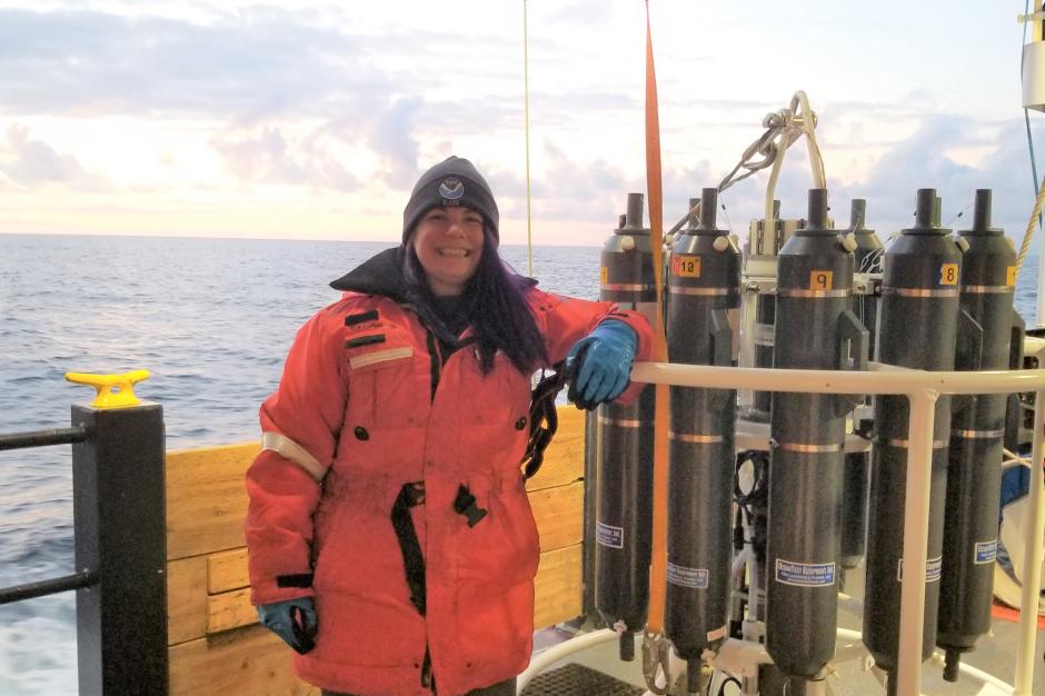 A female senior survey technician on aboard a ship with a water sampling instrument