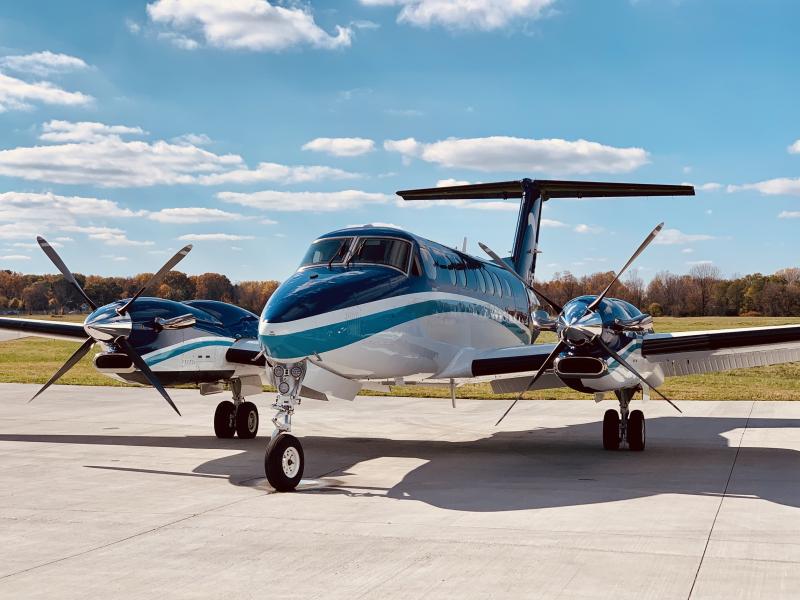 A small blue and white turboprop on the tarmac on sunny day