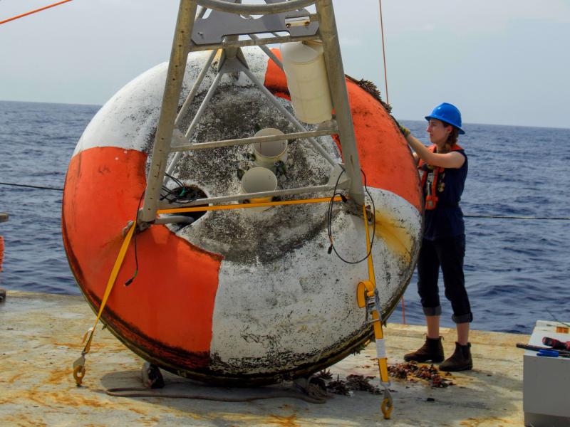 A crew member works on a bouy on the deck of a ship