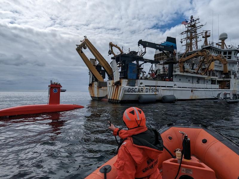 An uncrewed surface vehicle behind NOAA Ship Oscar Dyson