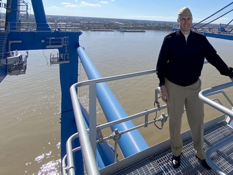 RDML Ben Evans stands atop a structure over the water.