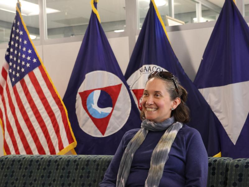 Alexis Gutierrez with flags in the background. Credit: NOAA/Eliza Mills