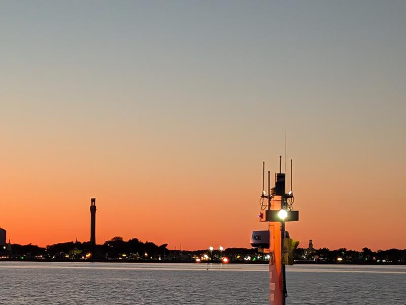 A red DriX uncrewed surface vehicle sails into the sunset