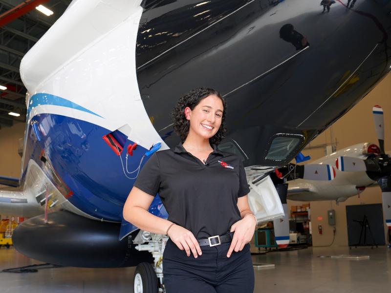 Sofia de Solo stands in front of nose of NOAA WP-3D Orion aircraft