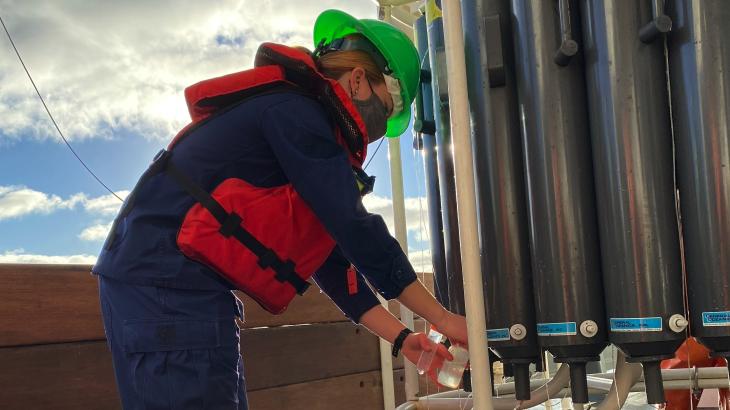 Lt. j.g. Edmonds is on the left collecting water samples from a CTD device on the right. 