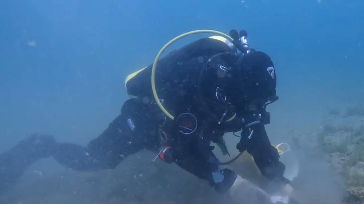 A scuba diver taking a sample from the bottom of a lake