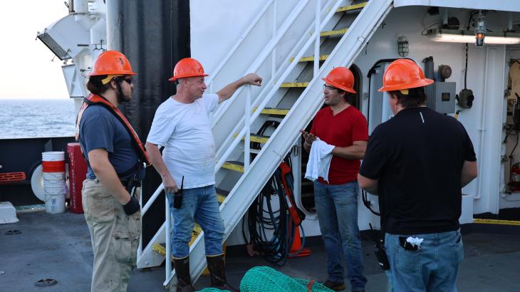 A group of crew members meet on the deck of a NOAA ship