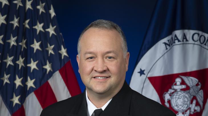 Rear Admiral Chad Cary with U.S. and NOAA Corps flags behind him