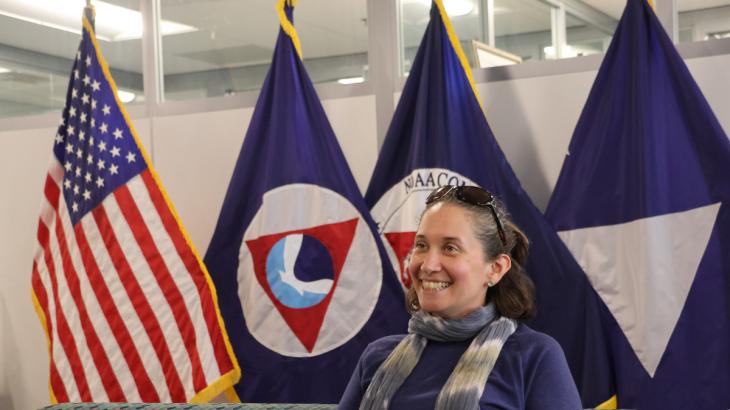 Alexis Gutierrez with flags in the background. Credit: NOAA/Eliza Mills