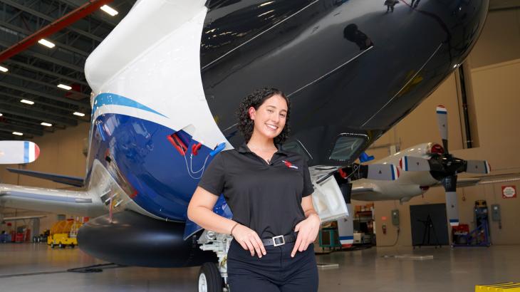 Sofia de Solo stands in front of nose of NOAA WP-3D Orion aircraft