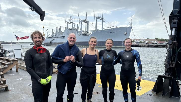 5 people standing on the deck of a ship after diving. 