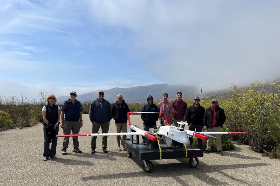 A group of people standing behind an uncrewed aircraft